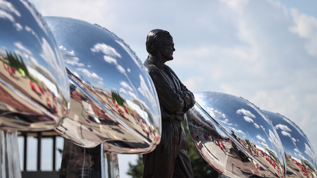 Lamar Hunt statue surrounded by four oversized Lombardi trophies